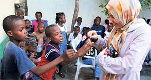 A volunteer with Hizmet organization Kimse Yok Mu with victims of the earthquake in Haiti.